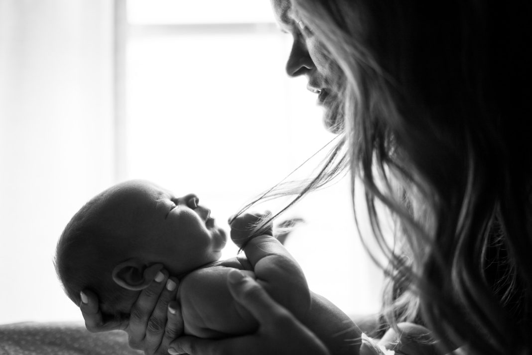 Мама держит на руках младенца (черно-белое фото)