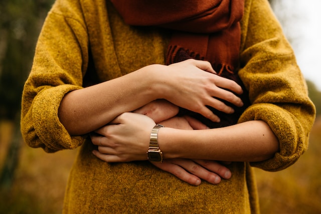 Женщина обнимает свой беременный живот